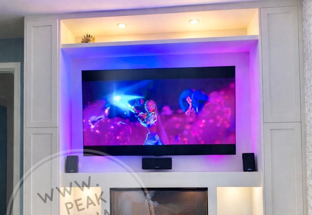 White media wall with LED alcove lighting, inset fire and fitted storage by Peak Media Walls